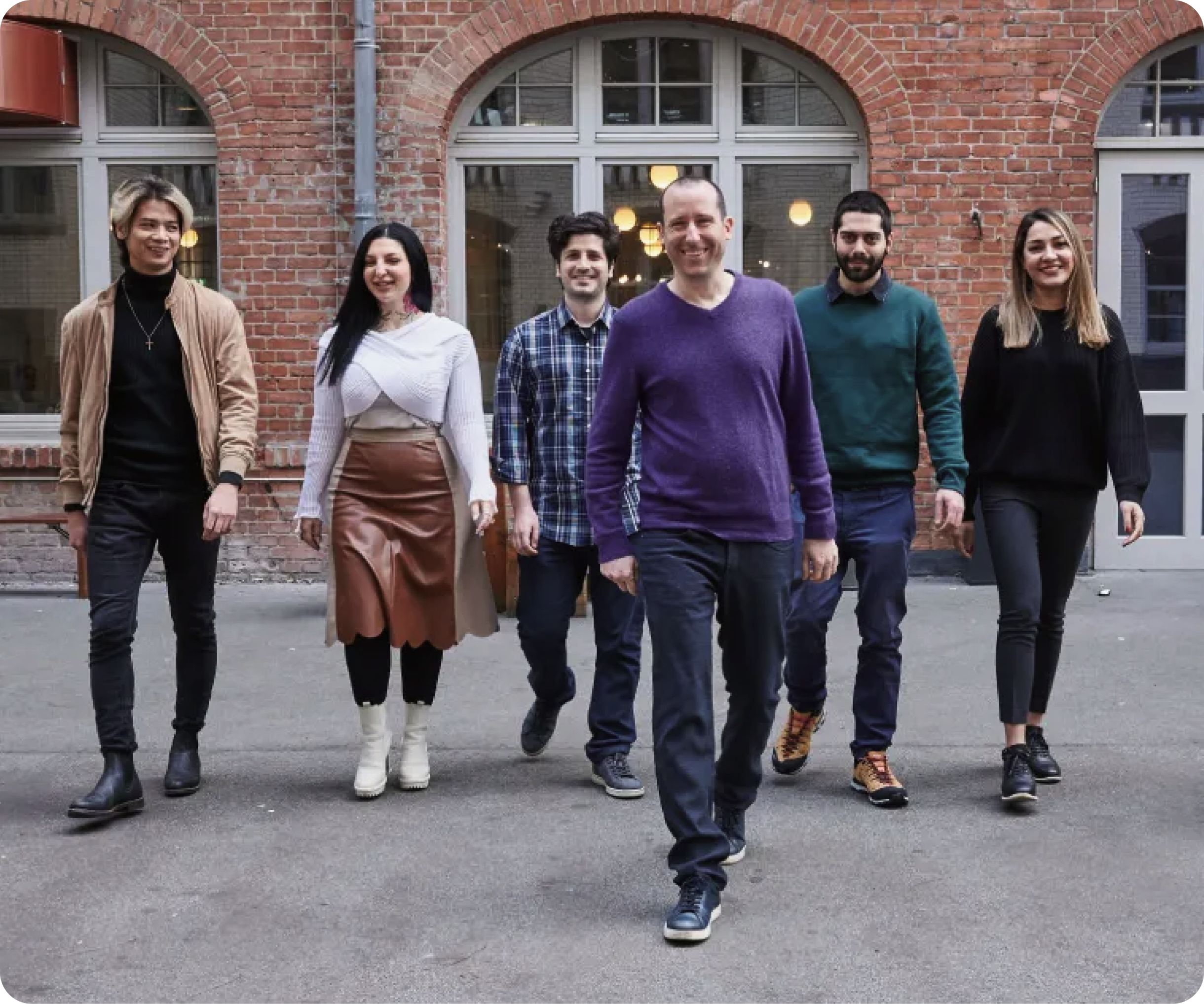 24metrics employees walking toward the camera on a rooftop in Berlin, with CEO Sven in front and a brick wall behind them.